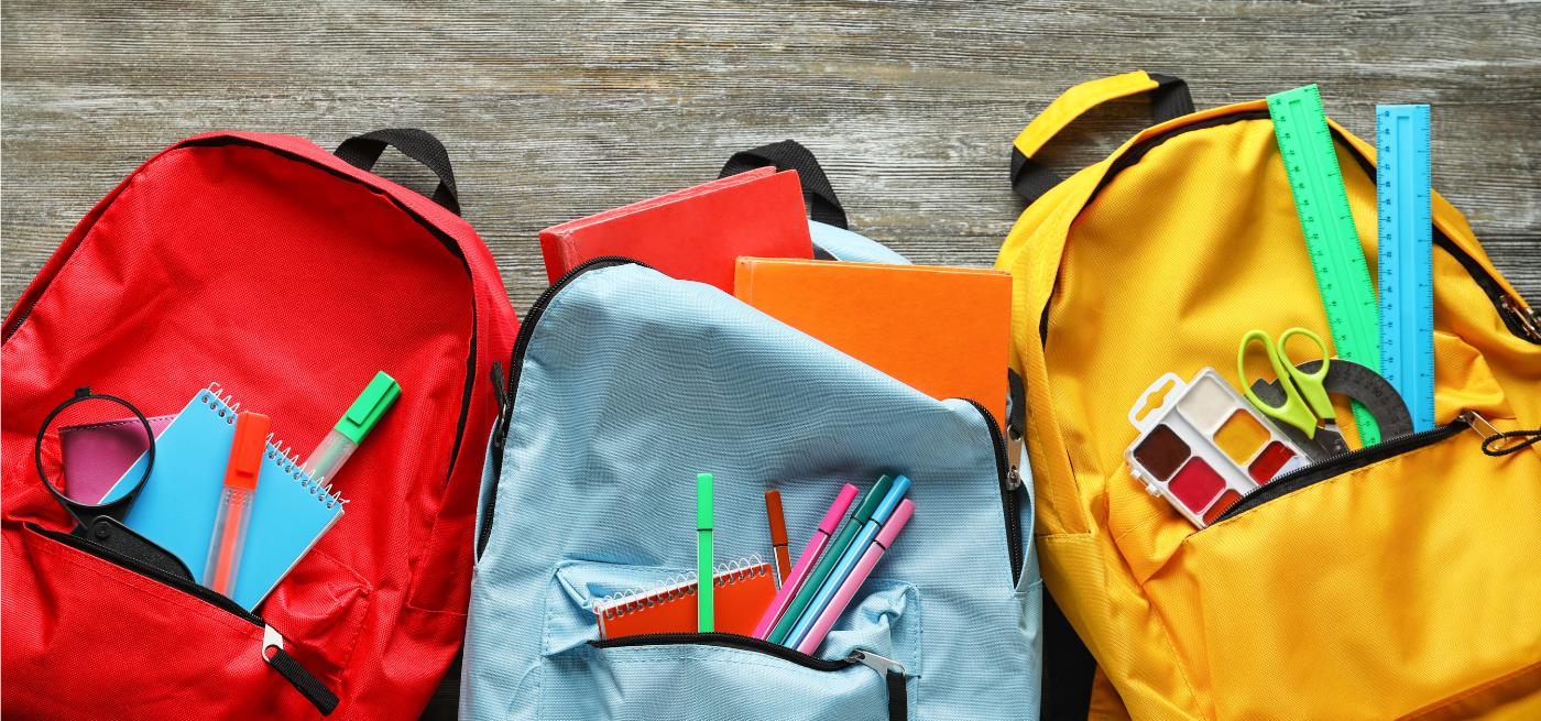 Três mochilas coloridas abertas com material escolar visível, incluindo cadernos, canetas e réguas